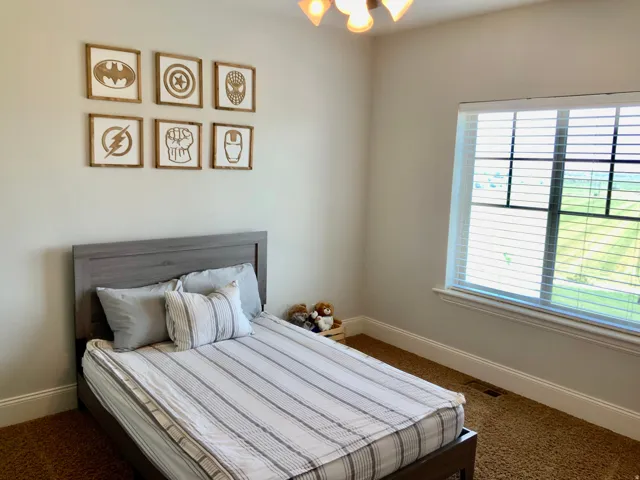 Room featuring a window with blinds, light-colored walls, and a gray-toned bed frame