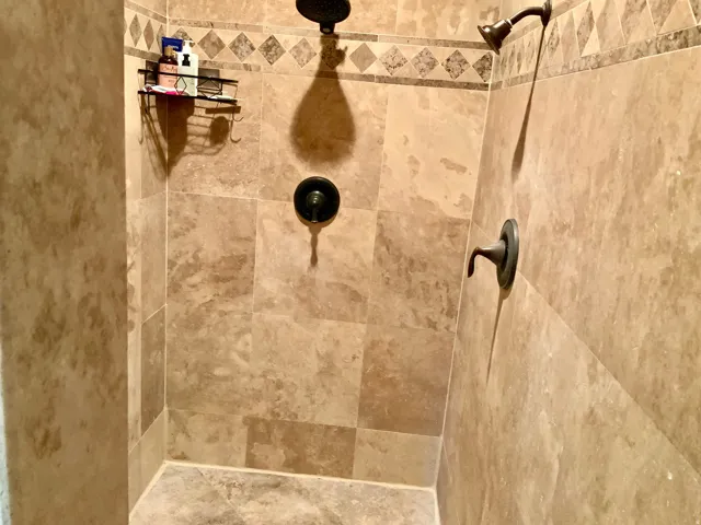 Tiled shower with a decorative border, dual shower heads, and oil-rubbed bronze fixtures