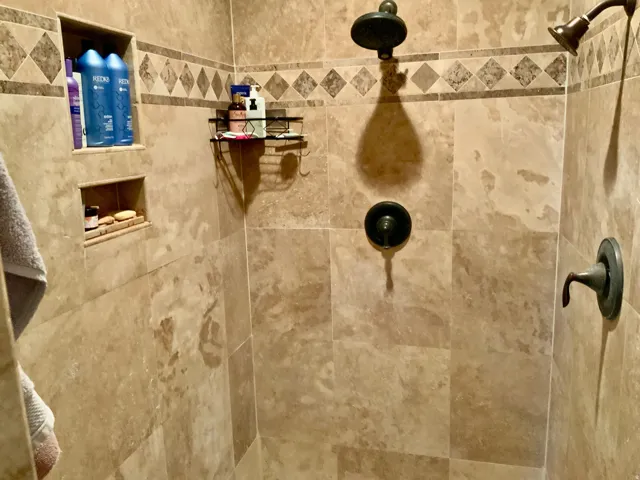 Tiled shower with integrated niches, decorative accent border, and dual shower heads