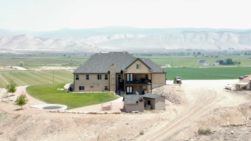 Spacious residence featuring a two-story exterior, multiple outdoor decks, a large backyard with a lawn area, and two additional outdoor structures