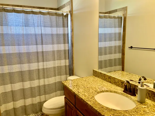 Bathroom vanity featuring a speckled countertop, an undermount sink, and dark bronze hardware