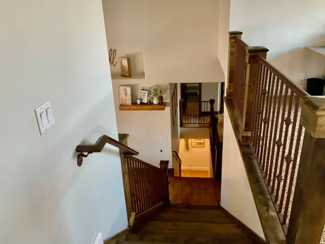 Multi-level interior staircase with wood-finish flooring, dark wood handrails, and decorative metal balusters