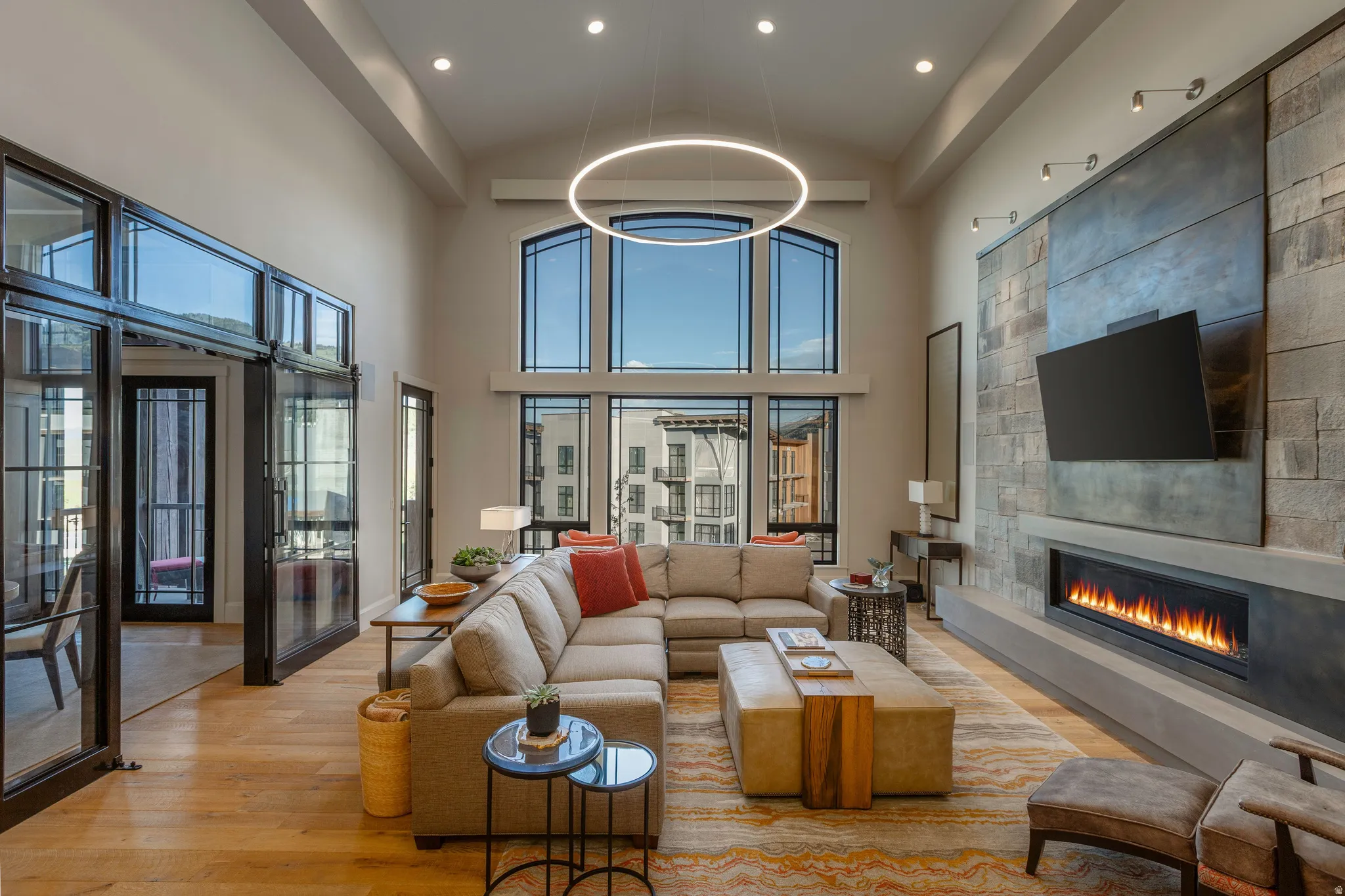 Vaulted living space with a floor-to-ceiling fireplace featuring a stone and panel accent wall