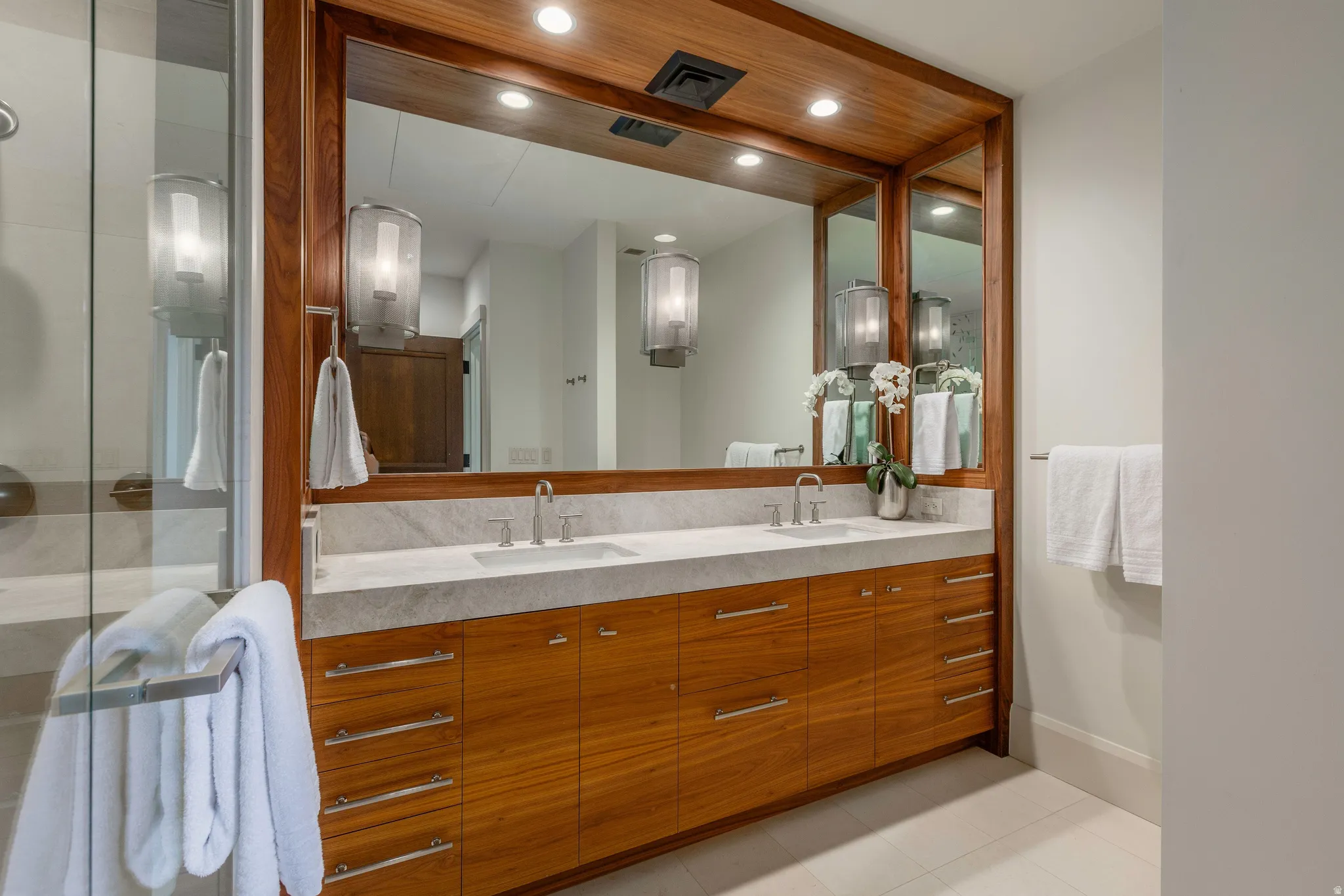 Bathroom featuring a dual vanity with a light-toned countertop, wood-finish cabinetry, and contemporary vessel sinks