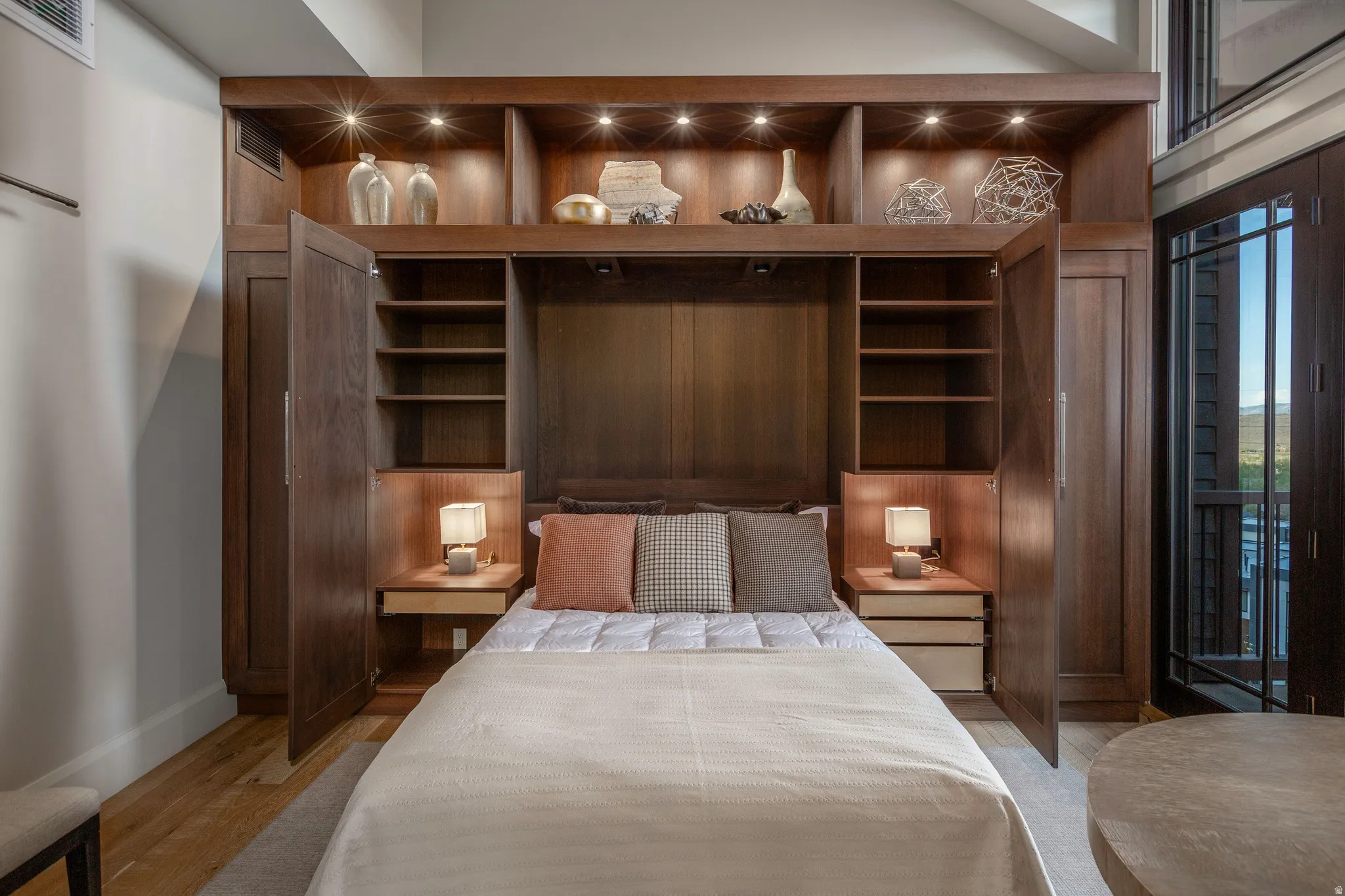 Integrated custom cabinetry with built-in bed frame, recessed lighting, and shelving