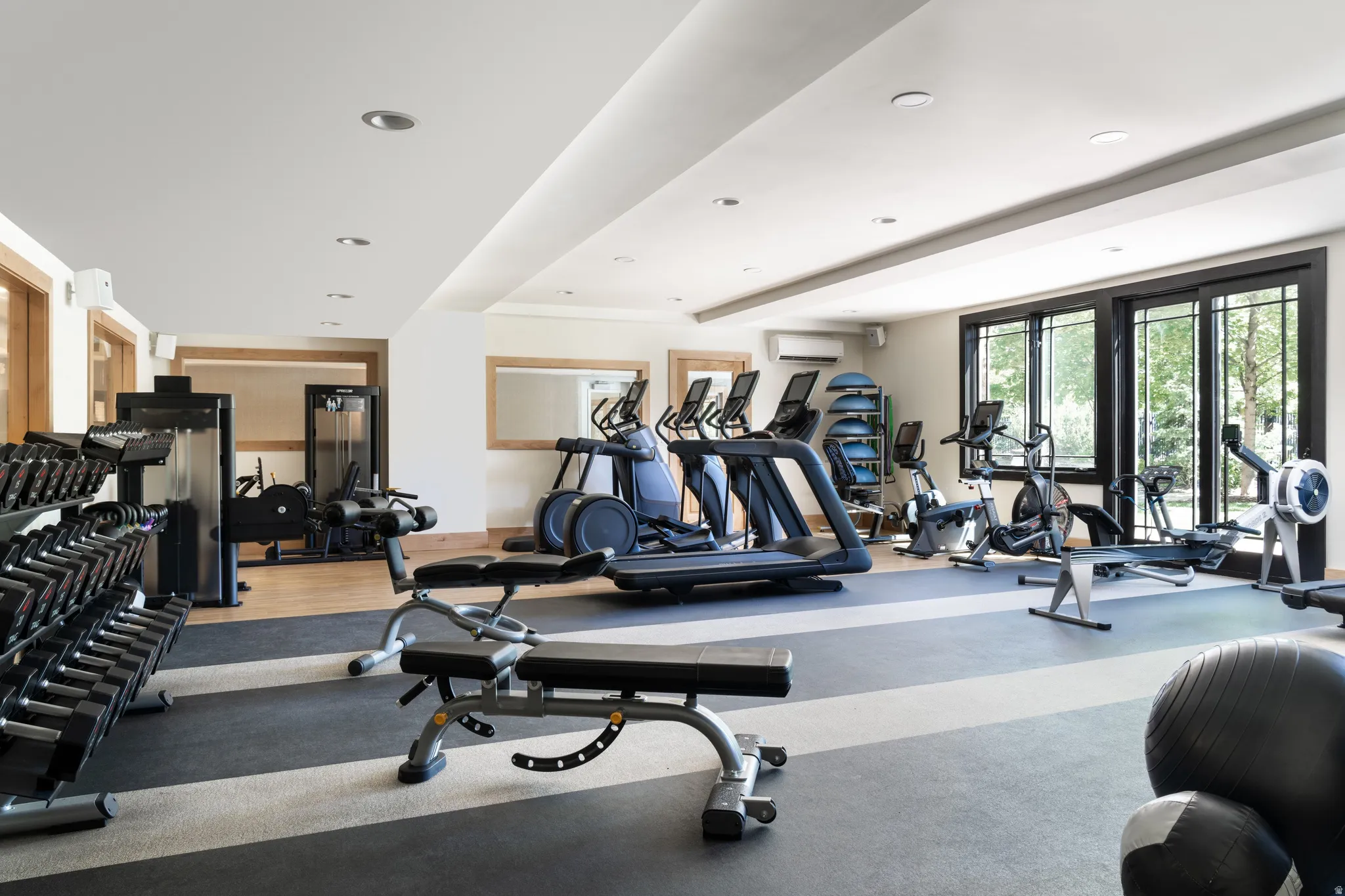 Dedicated fitness space featuring rubber flooring, recessed lighting, expansive windows, and a mirrored wall