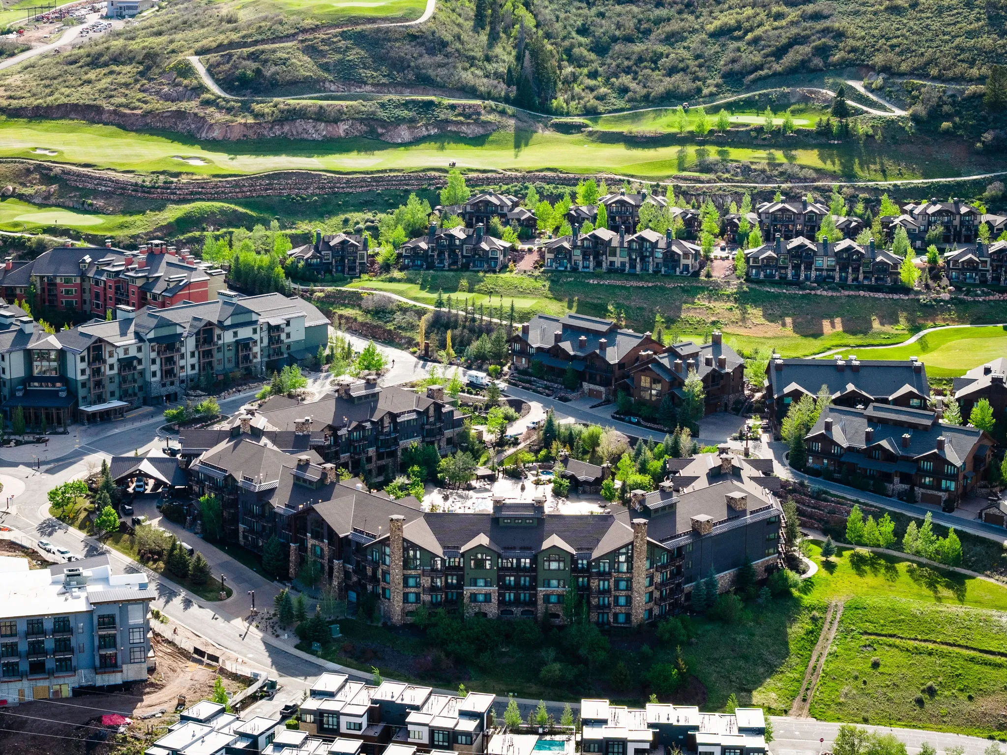 Extensive residential development featuring multi-story buildings and individual homes nestled into a green, mountainous landscape