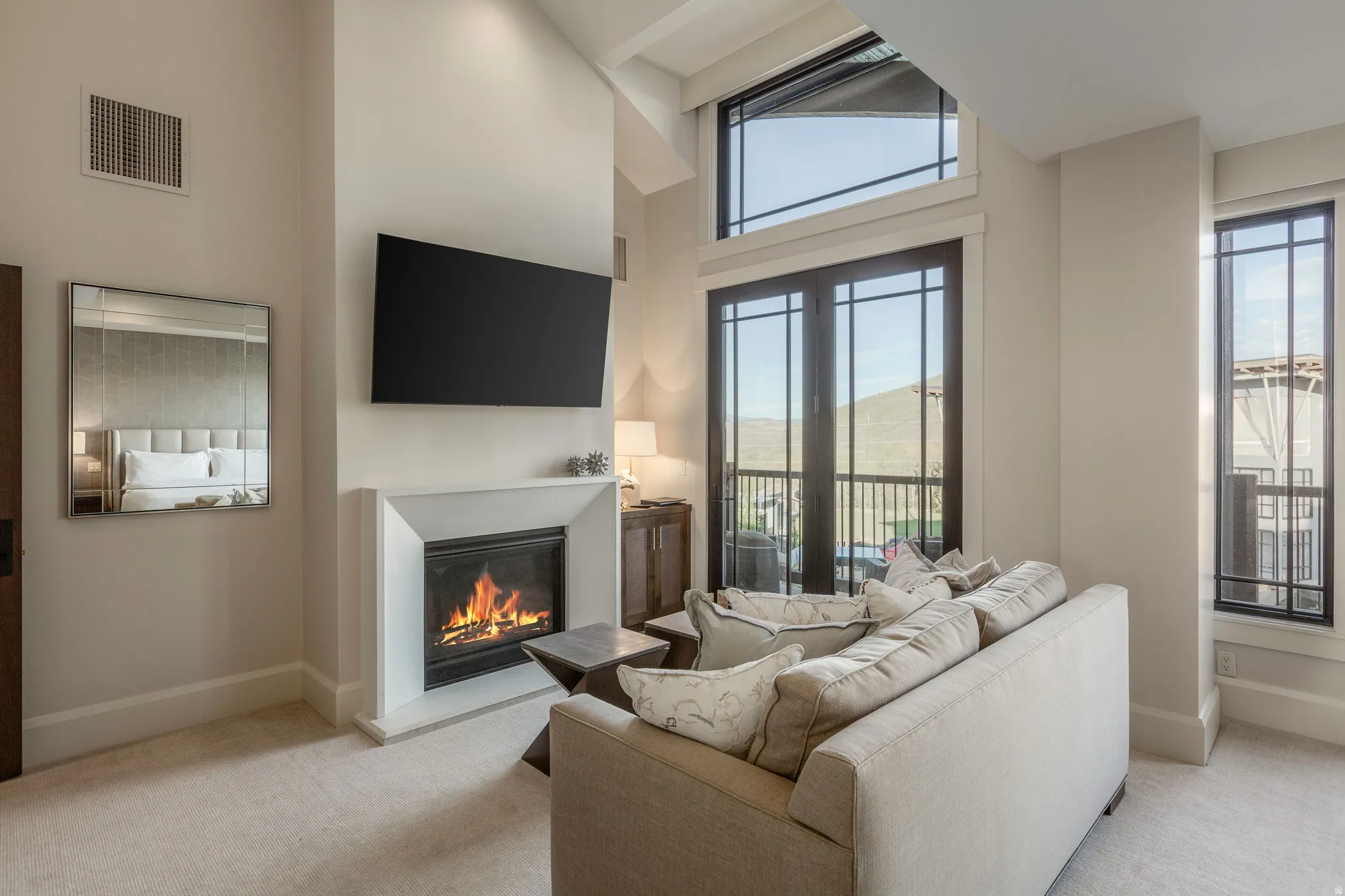 Vaulted ceilings featuring a recessed light fixture, a fireplace with a white surround, and an integrated wall-mounted television