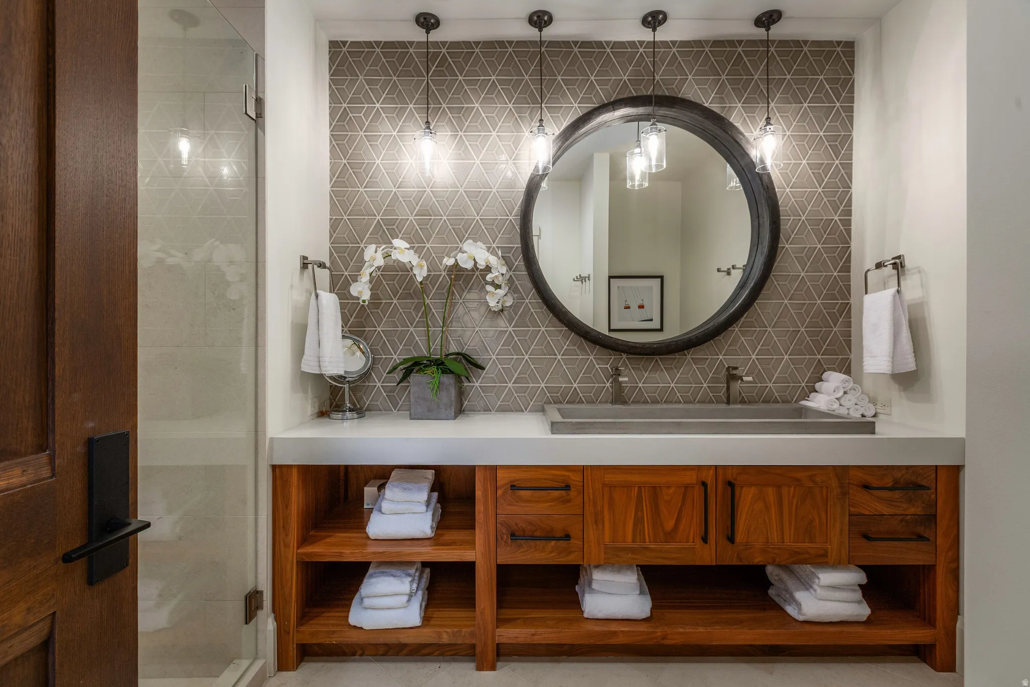 Bathroom vanity featuring a concrete vessel sink, modern wall-mounted faucet, and a large round mirror