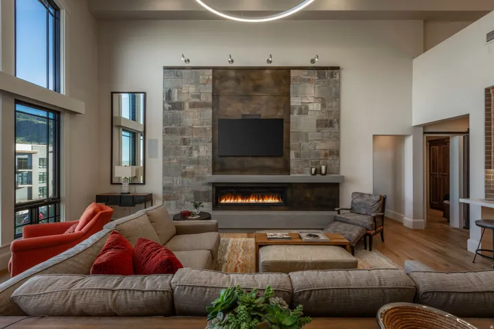 Contemporary living space featuring a floor-to-ceiling stone and dark panel fireplace surround with an integrated linear firebox