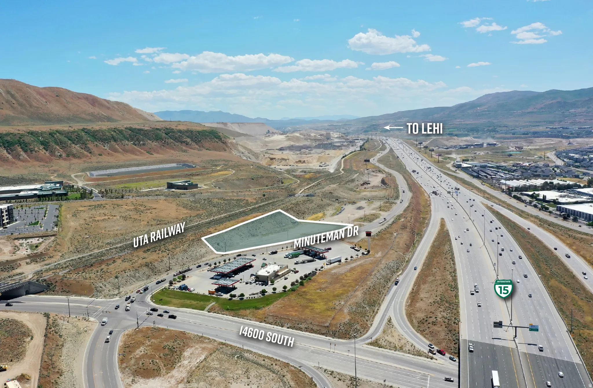 Aerial perspective showcasing a parcel of undeveloped land bordered by an active railway line, Minuteman Drive, and a major highway