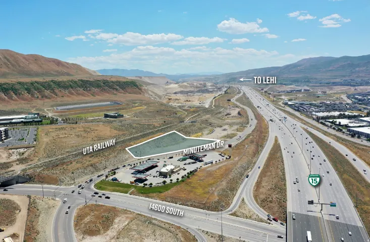 Aerial perspective showcasing a parcel of undeveloped land bordered by an active railway line, Minuteman Drive, and a major highway