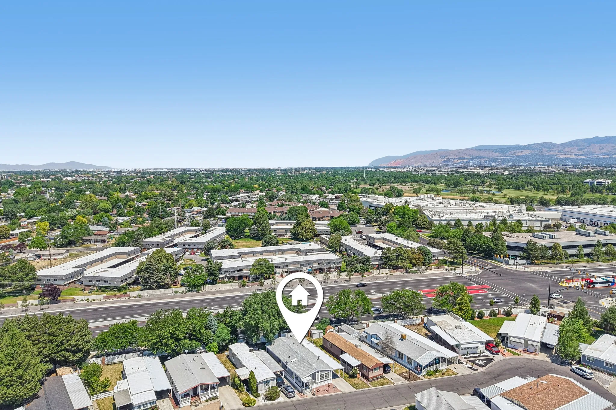 Aerial perspective showcasing a residential community with abundant mature trees and distant mountain ranges