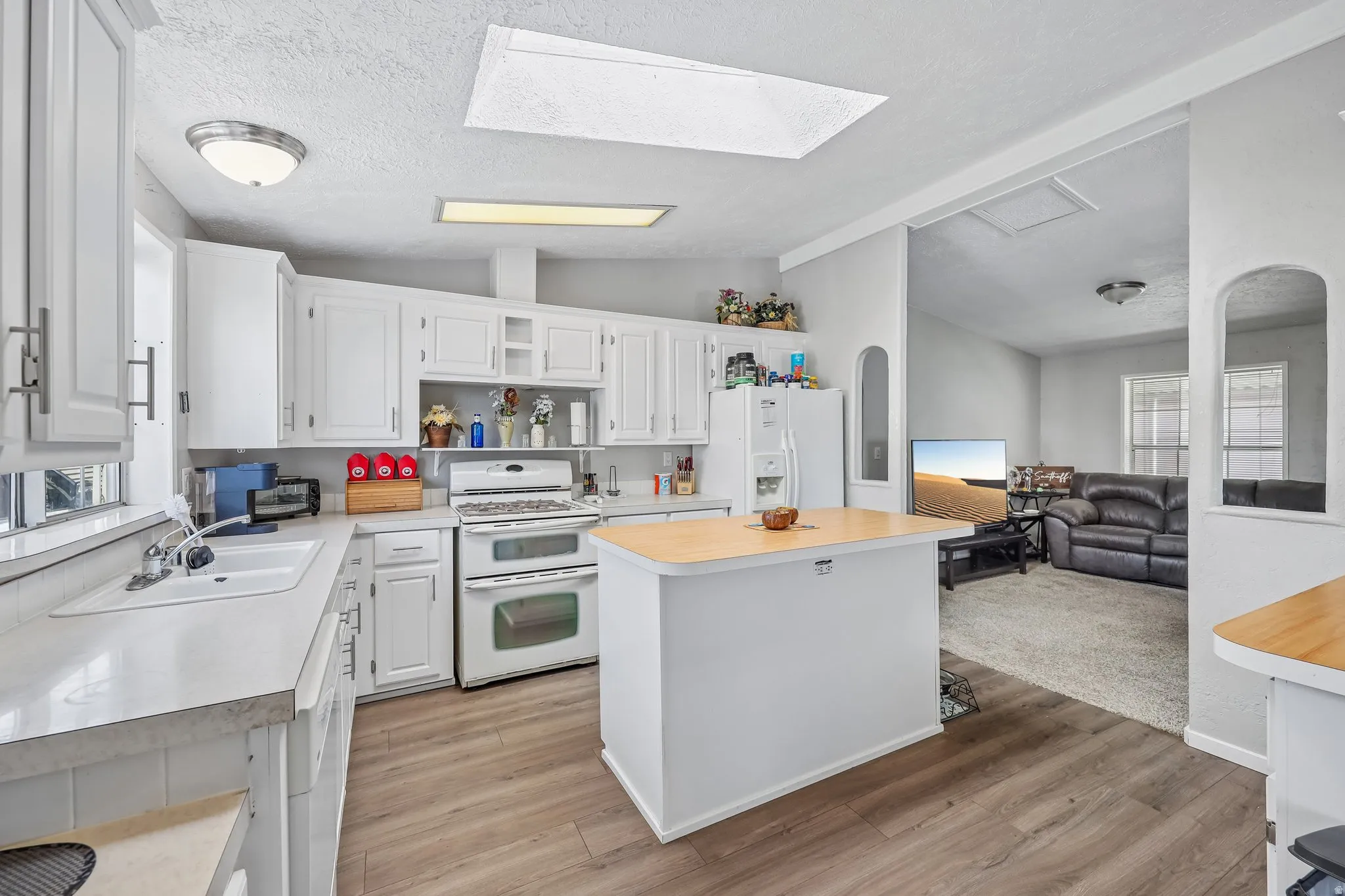Kitchen featuring abundant white cabinetry, light-toned countertops, and wood-finish flooring