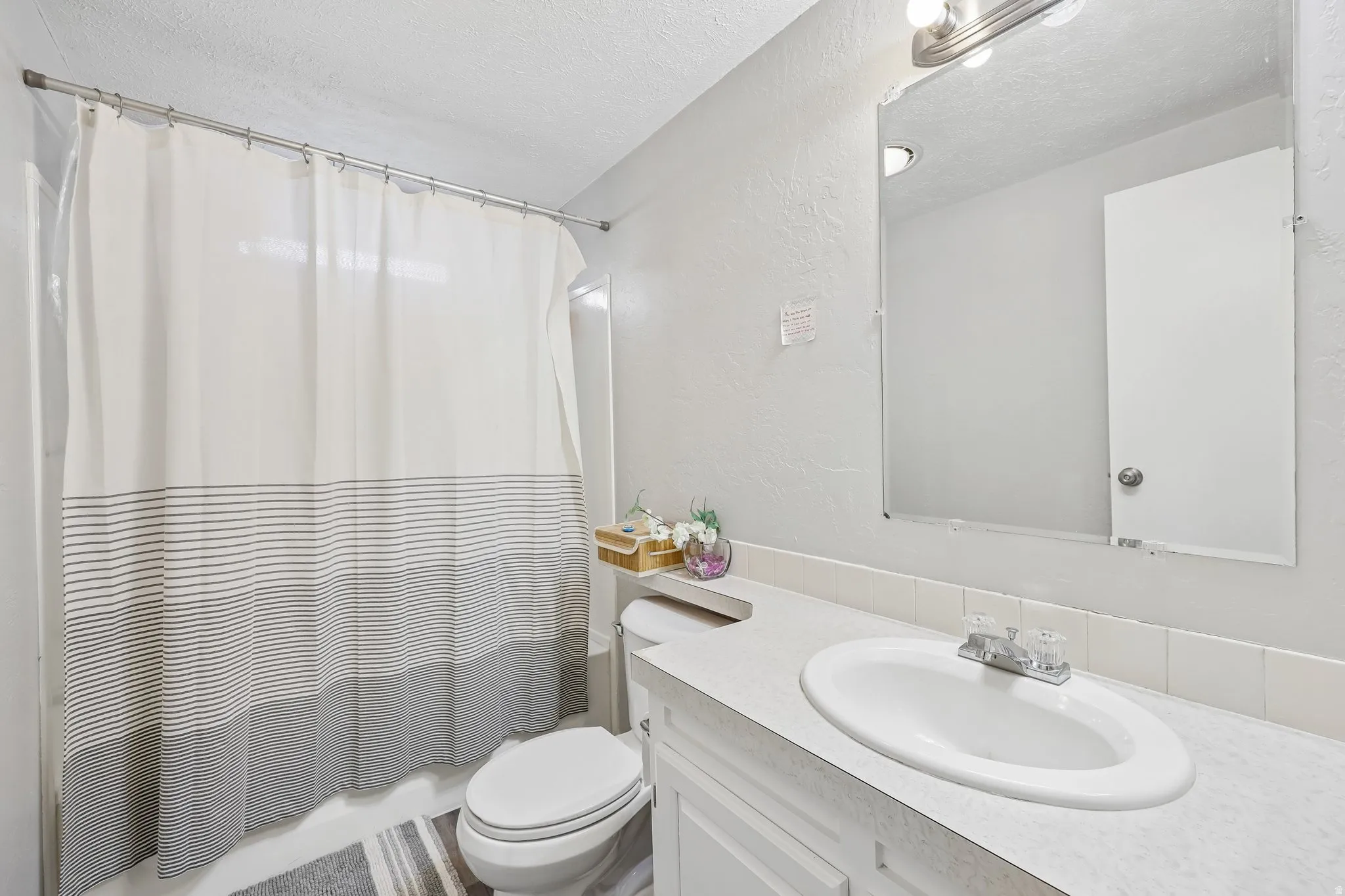 Bathroom featuring a full-size vanity with an integrated sink, a wall-mounted mirror, and a tub/shower combination