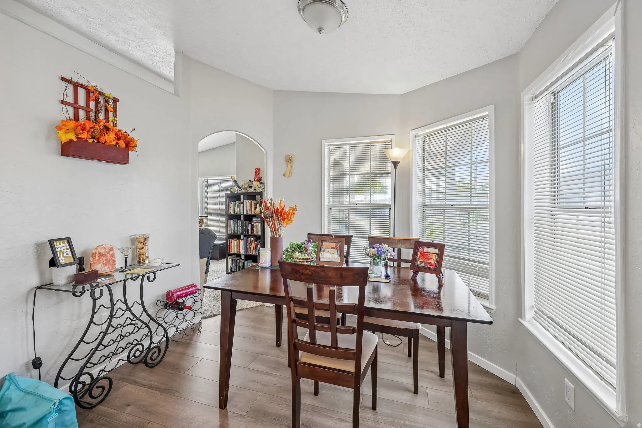 Dining area featuring wood-finish flooring, a tray ceiling, and an arched entryway