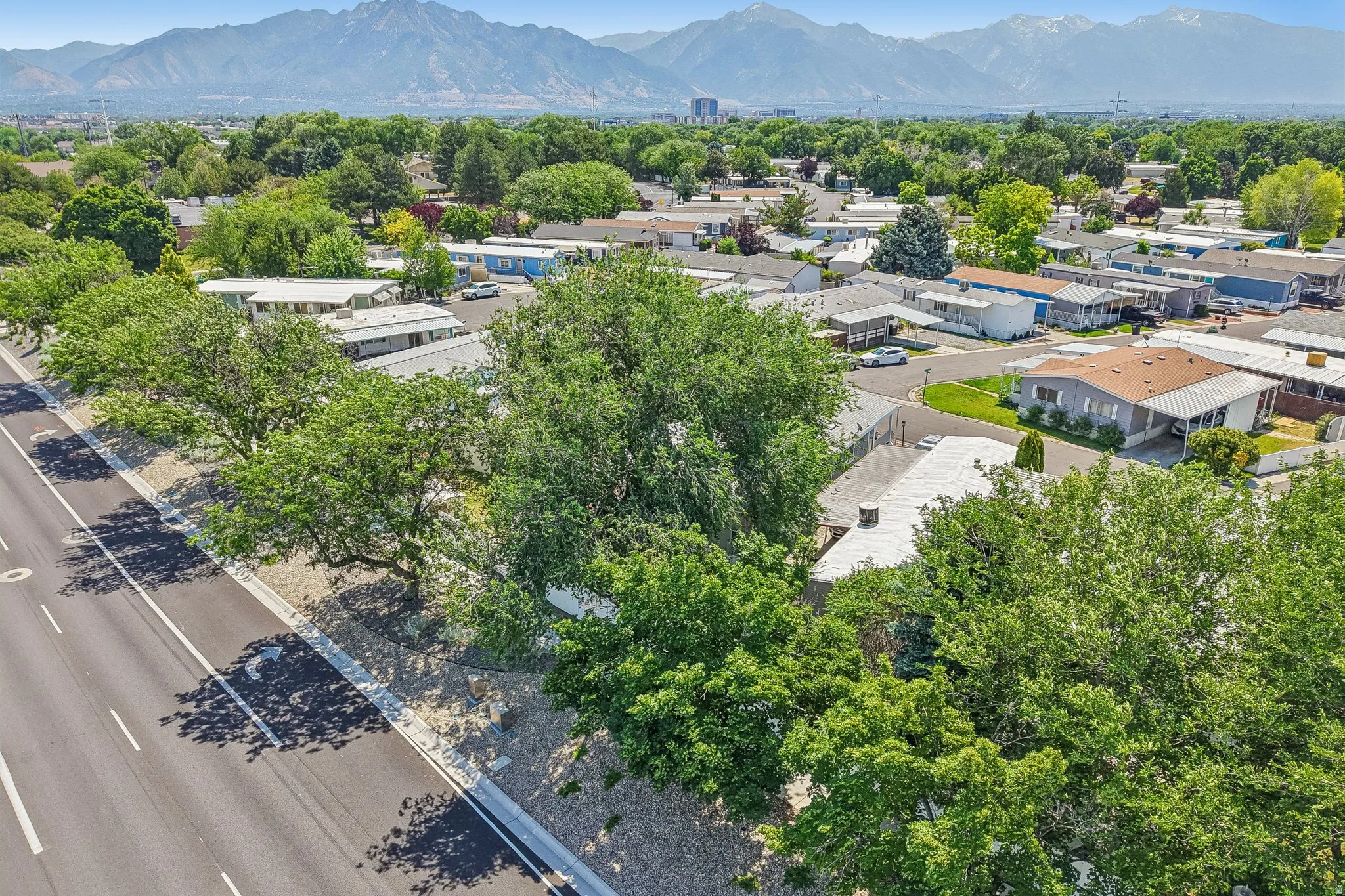 Aerial perspective showcasing a residential community with mature trees and mountain scenery