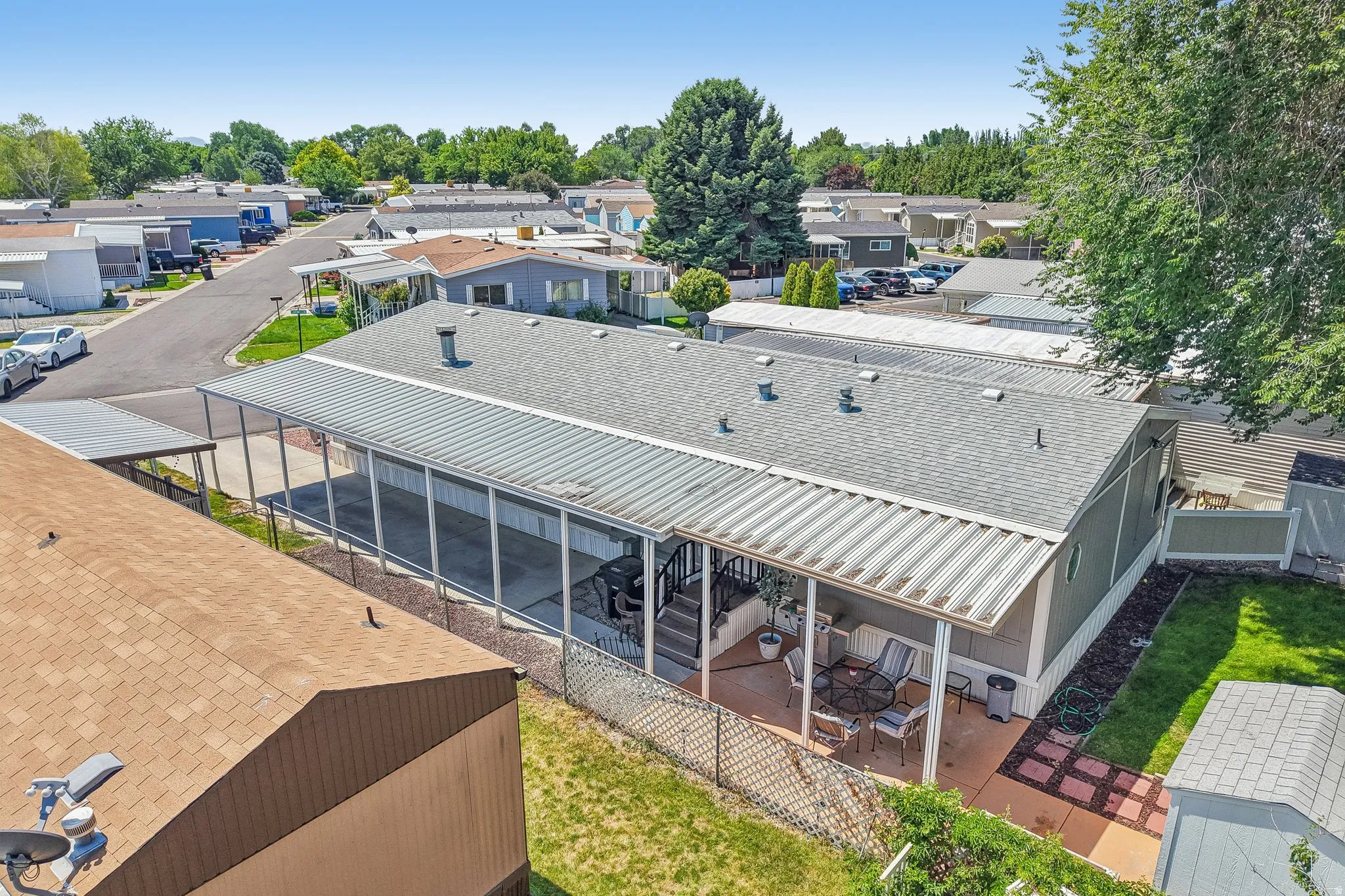 Manufactured home featuring a covered patio, a covered carport, and a fenced yard