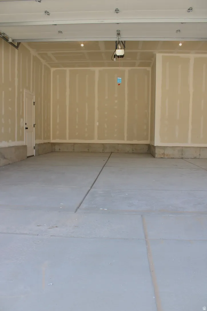 Spacious garage featuring a concrete floor, unpainted drywall, and an overhead garage door opener
