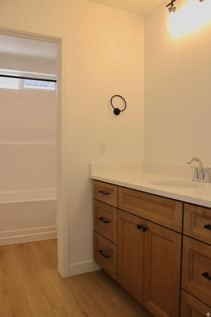Bathroom featuring a wood-finish vanity with a light-colored countertop and undermount sink