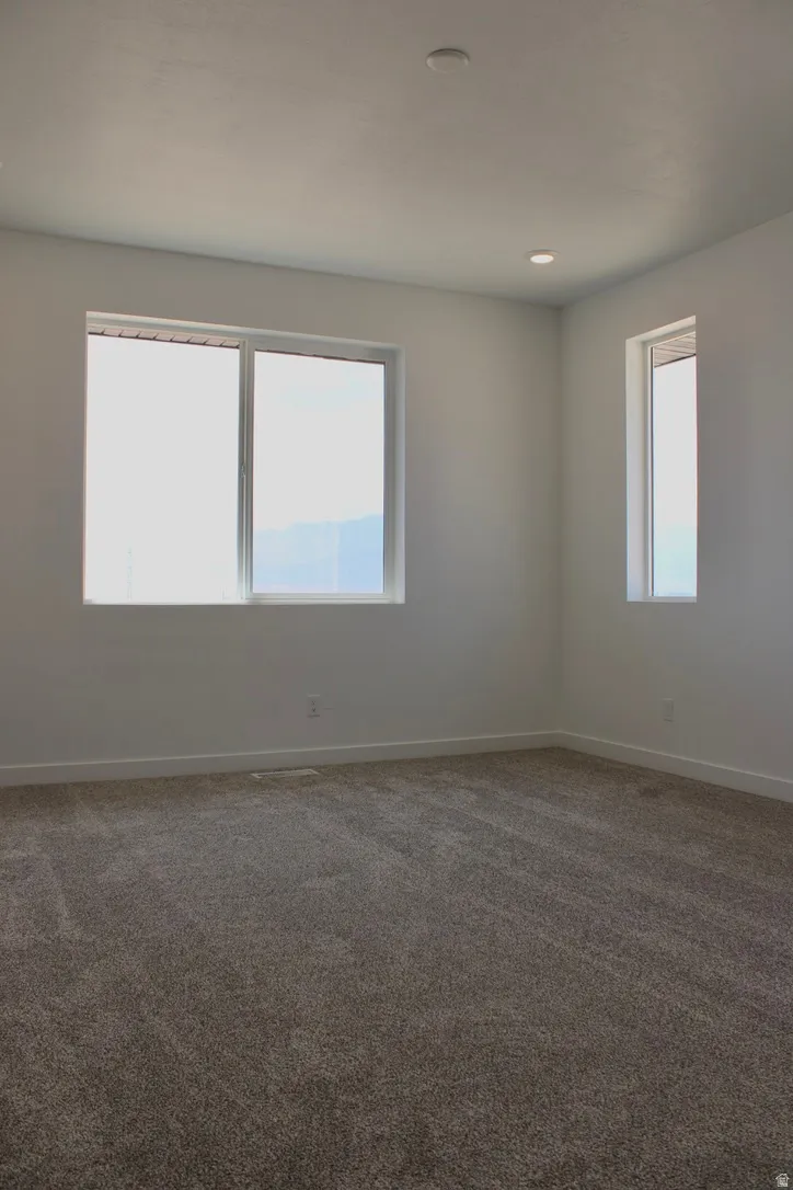 Expansive room featuring multiple windows, recessed ceiling lighting, textured wall finishes, and clean baseboard trim