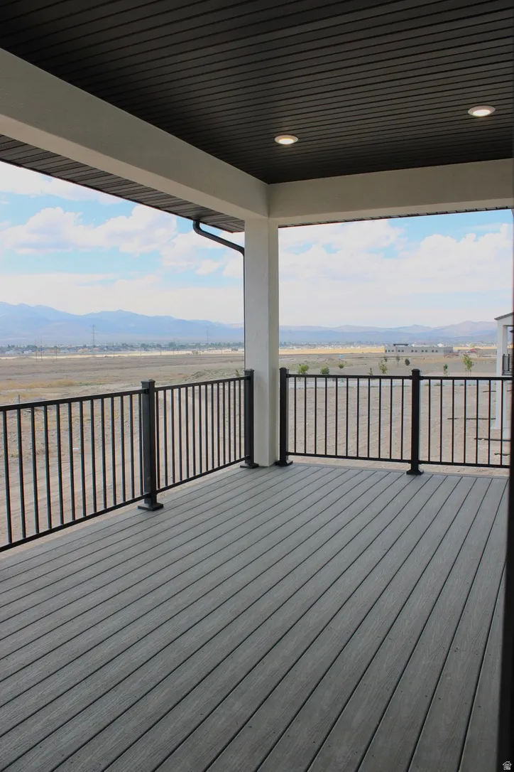 Covered outdoor deck with grey composite decking, black metal railings, and recessed ceiling lighting