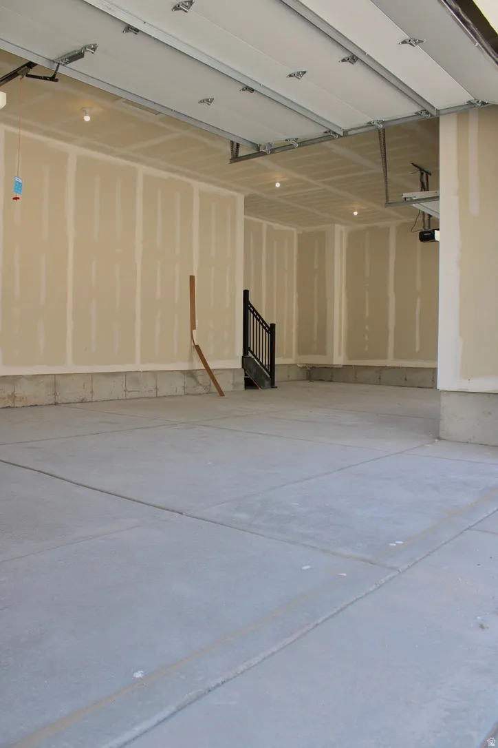 Spacious garage featuring a concrete floor, exposed drywall walls, and overhead lighting