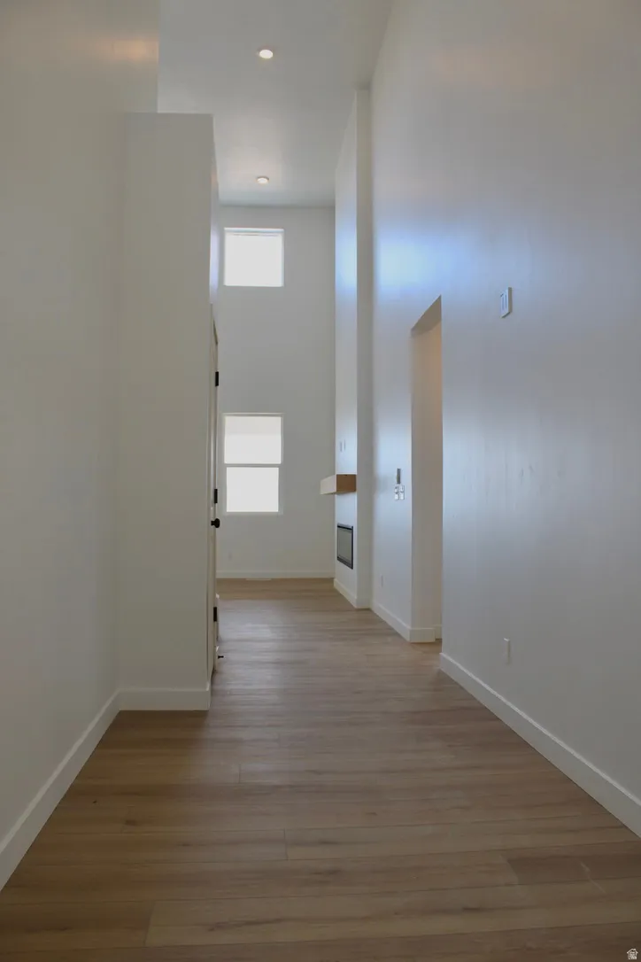 Open hallway featuring wood-finish flooring, recessed lighting, and high ceilings