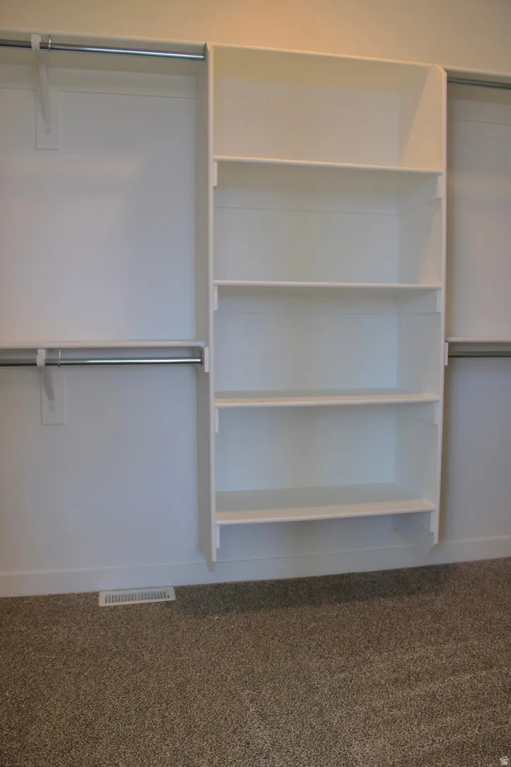Built-in white shelving system with four shelves, complemented by two chrome hanging rods on either side
