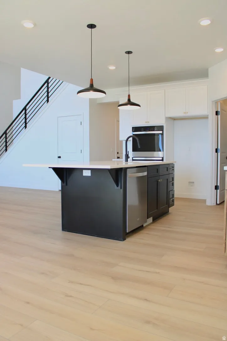 Open-concept kitchen featuring a dark-toned island with light-colored countertop, stainless steel appliances, and two contemporary pendant lights