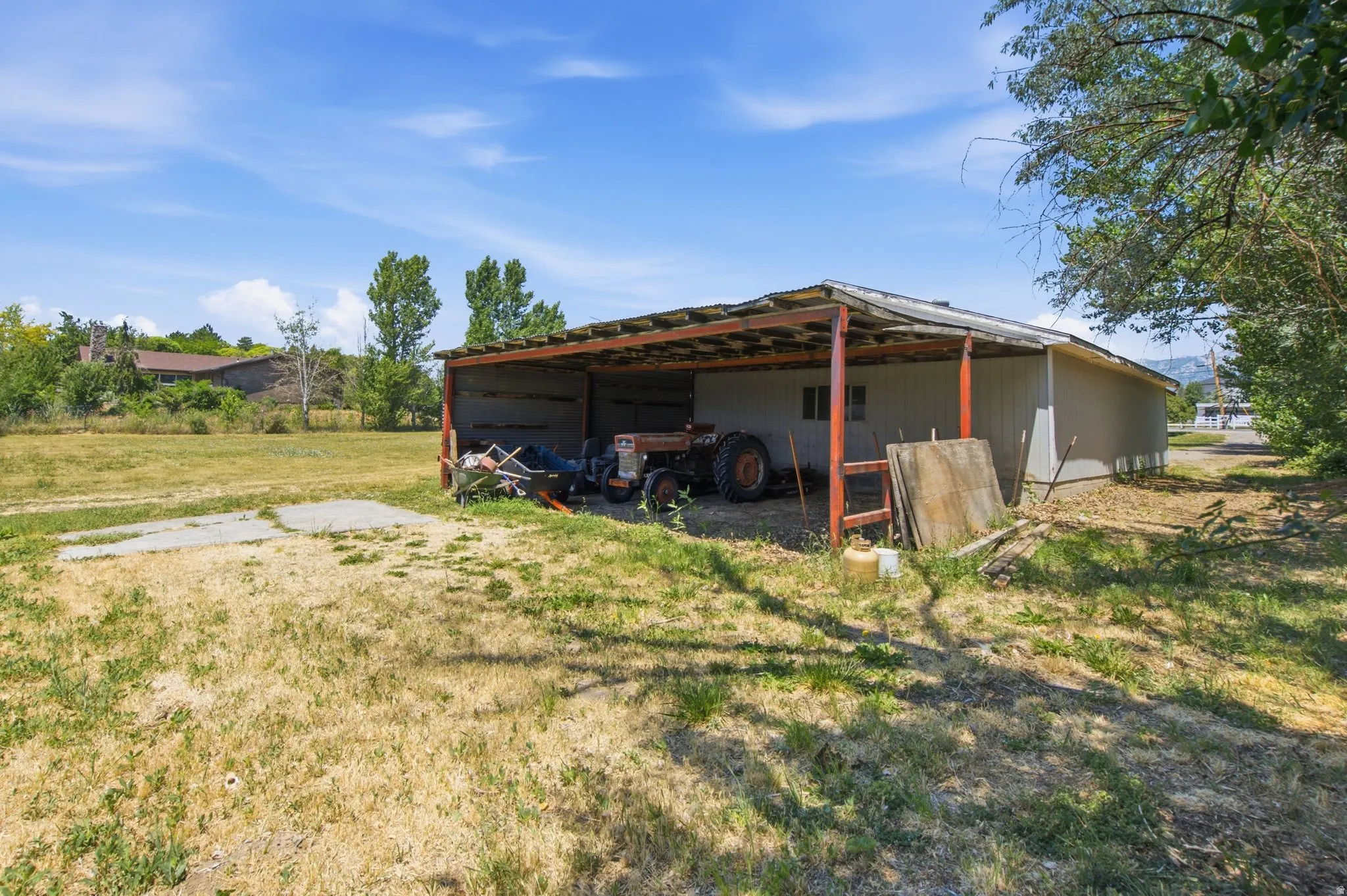 Open-sided shed with a metal roof and concrete pad