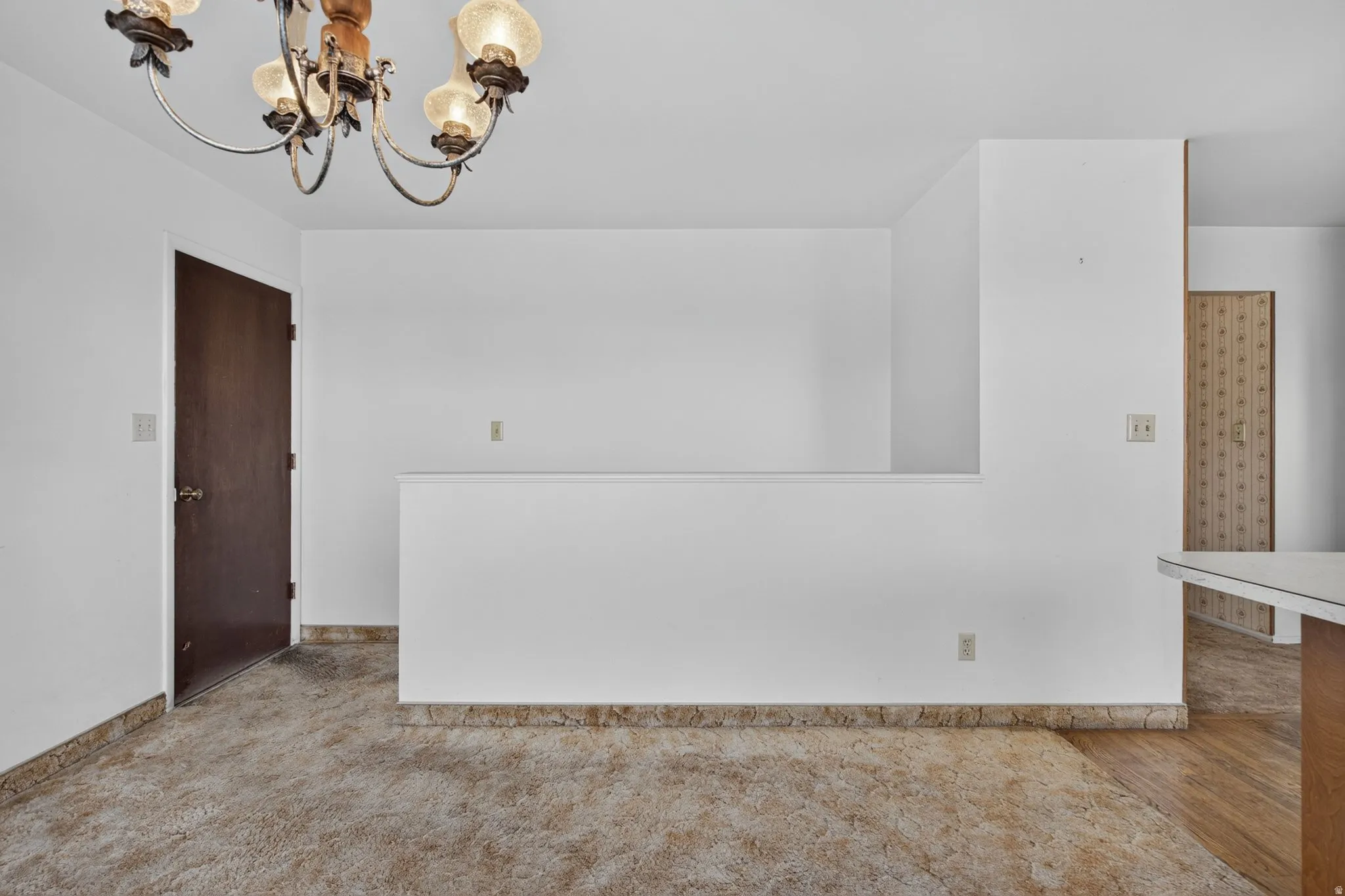 Open-concept interior featuring light-toned walls, a decorative ceiling fixture, and a partial wall separating spaces