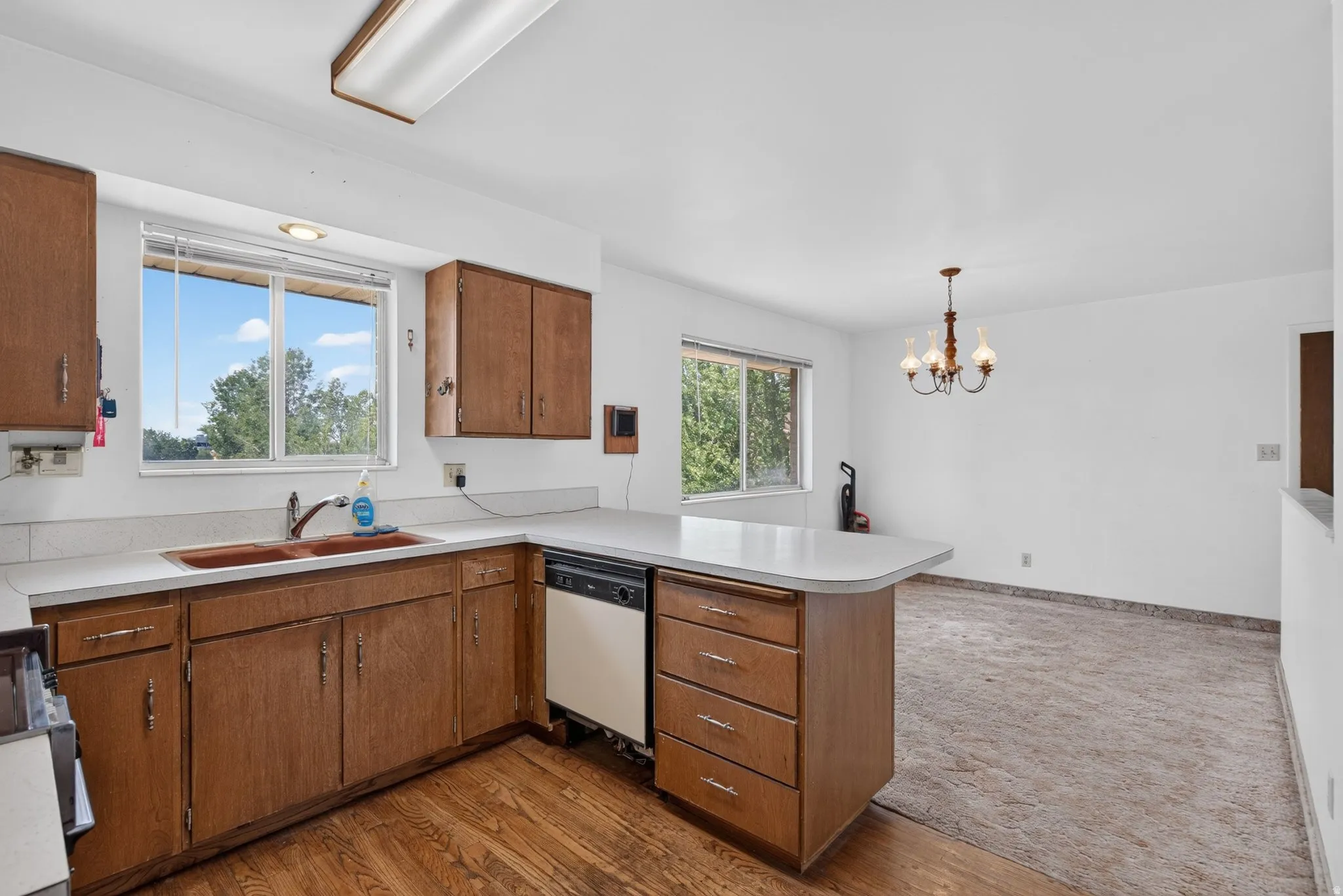 Kitchen featuring wood-finish cabinetry, light countertops, and a double-basin sink
