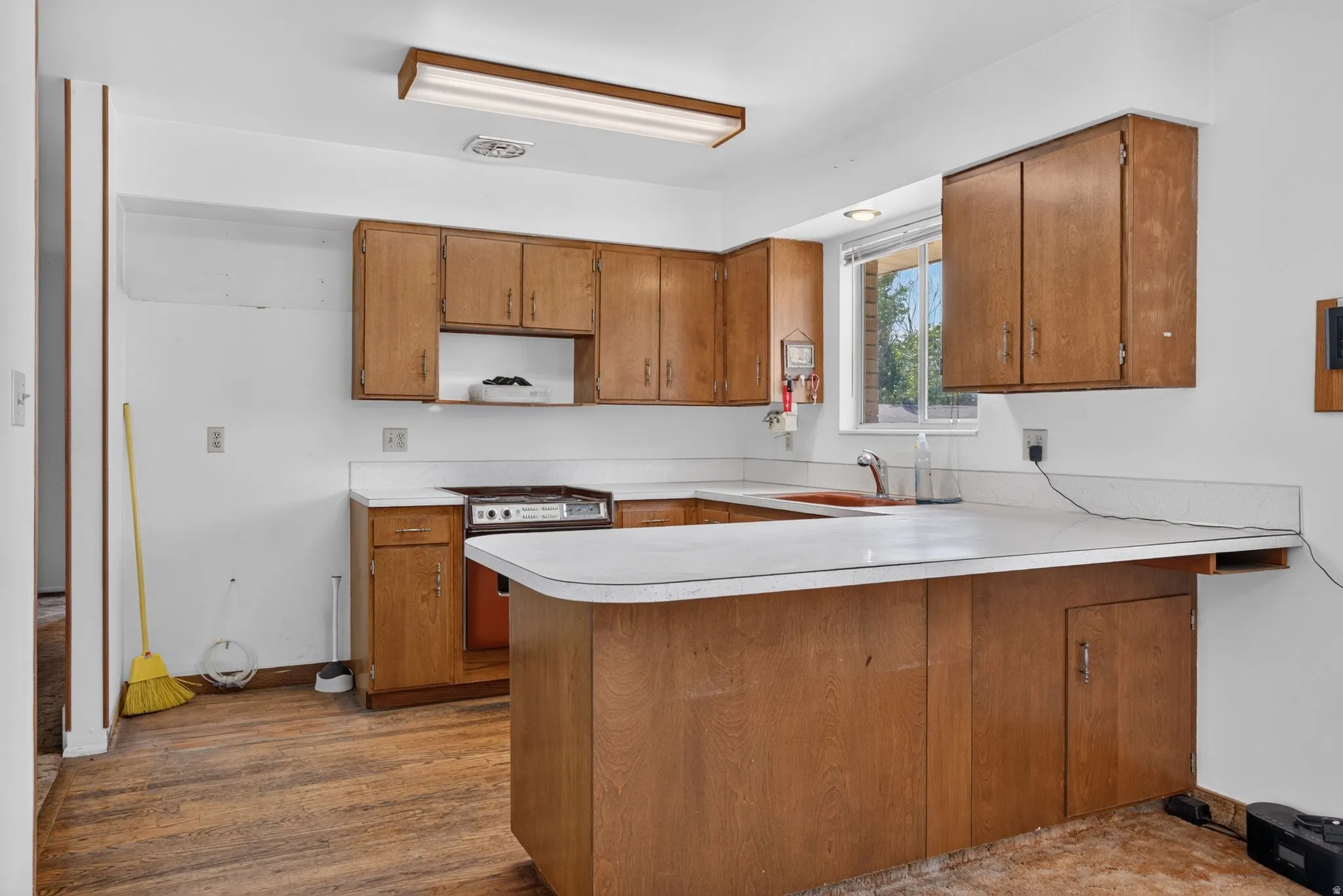 Kitchen featuring wood-finish cabinetry, white countertops, a built-in range, and a window above the sink