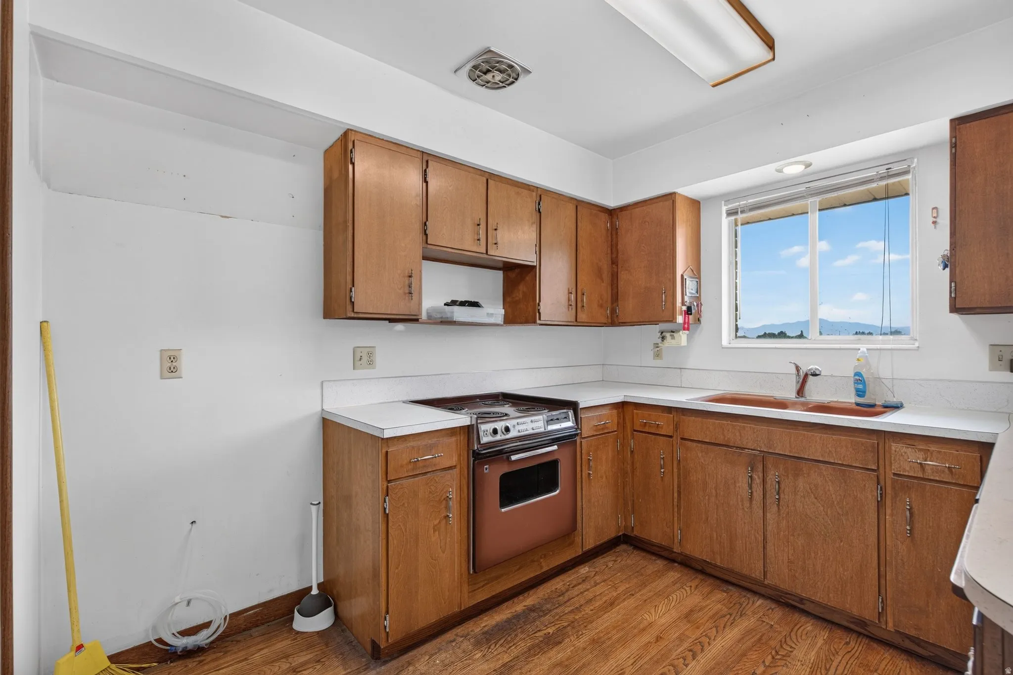 Kitchen featuring wood-finish flooring, wood cabinetry, white countertops, and a built-in range
