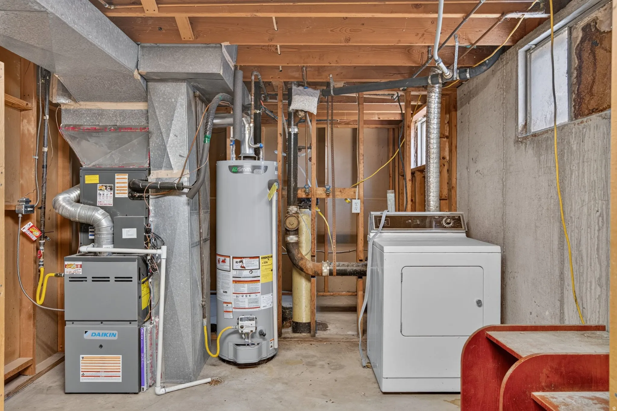 Basement utility area featuring a furnace, water heater, and laundry appliances