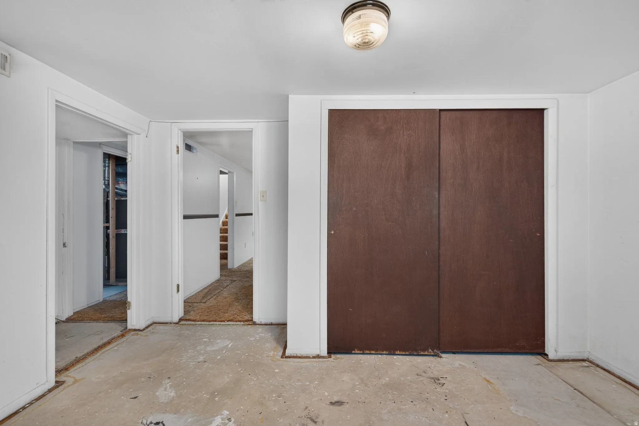 Interior space featuring a utility ceiling light fixture, concrete flooring, and white painted walls