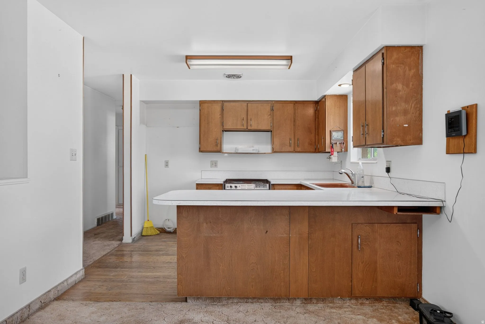 Kitchen featuring wood-finish cabinetry, white countertops, built-in sink, and a built-in range