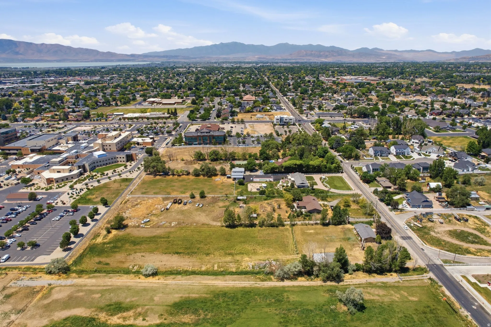 Expansive land parcel featuring open fields and mature trees, surrounded by residential areas and commercial structures
