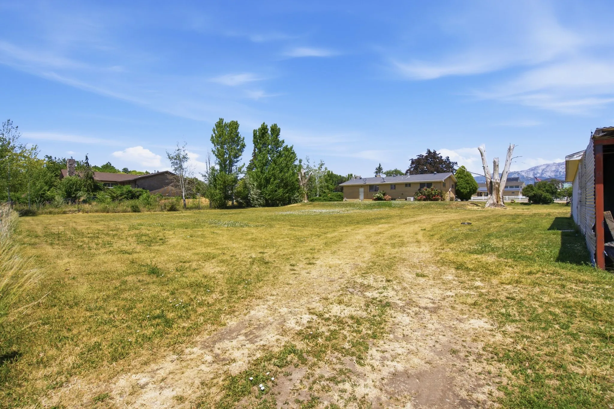 Expansive property grounds featuring a grass lawn and mature trees