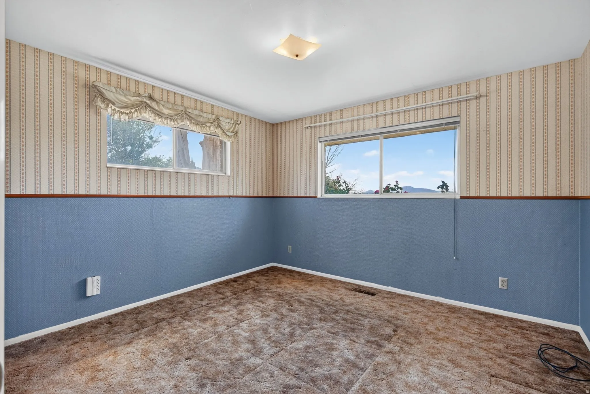 Room featuring two windows, crown molding, and a flush mount ceiling fixture