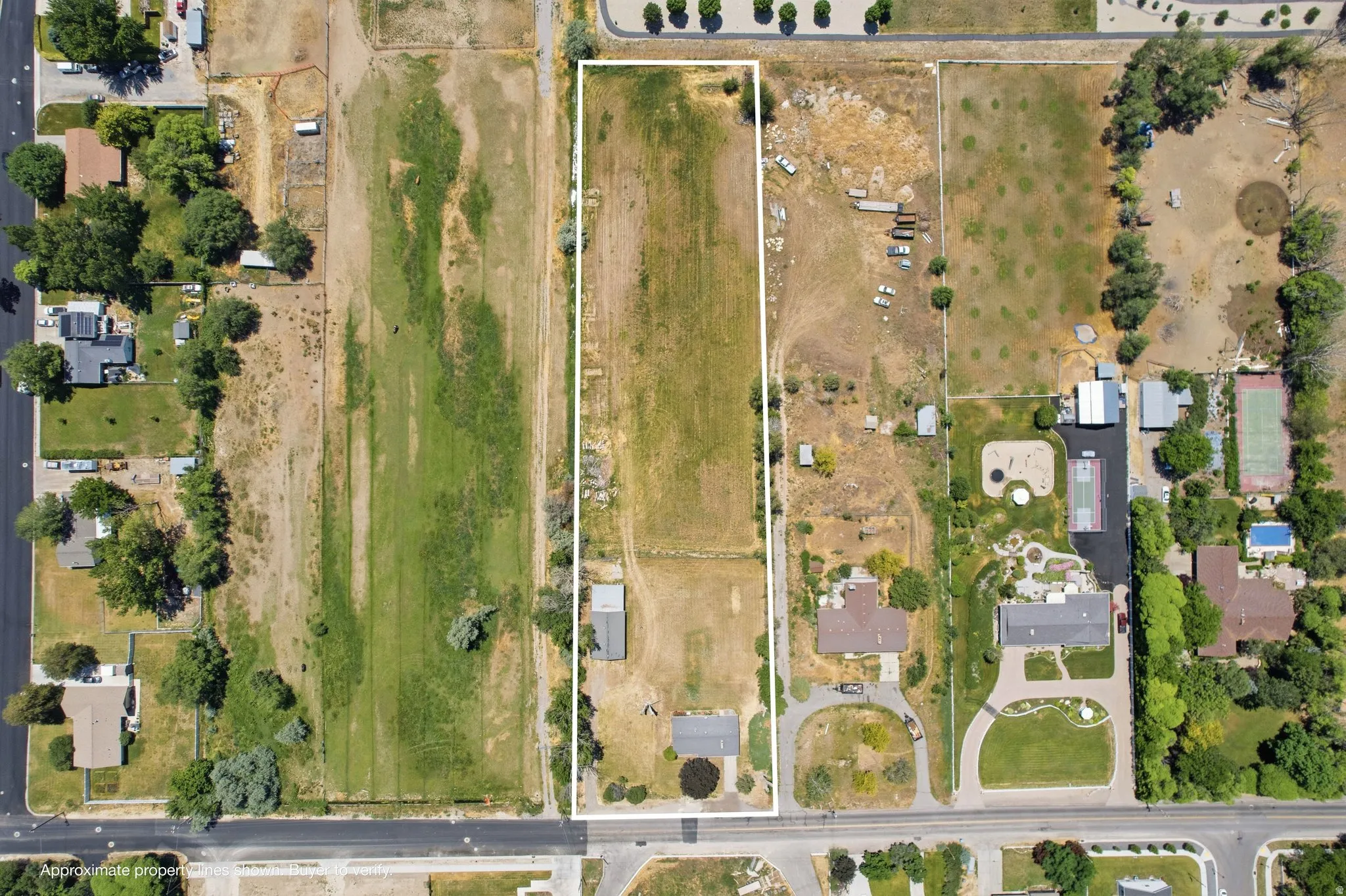 Expansive rectangular lot featuring a detached outbuilding and direct road frontage