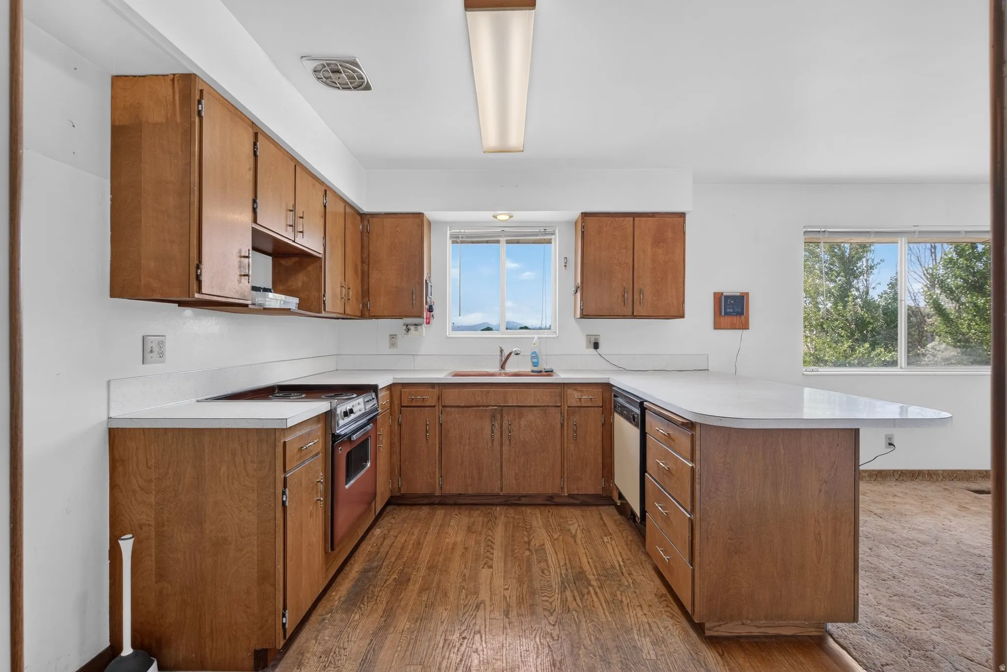 Kitchen featuring U-shaped wood cabinetry, white countertops, integrated range with oven, and wood-finish flooring