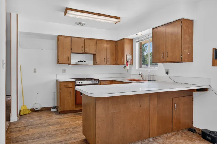 Kitchen featuring wood-finish cabinetry, white countertops, a built-in range, and a window above the sink