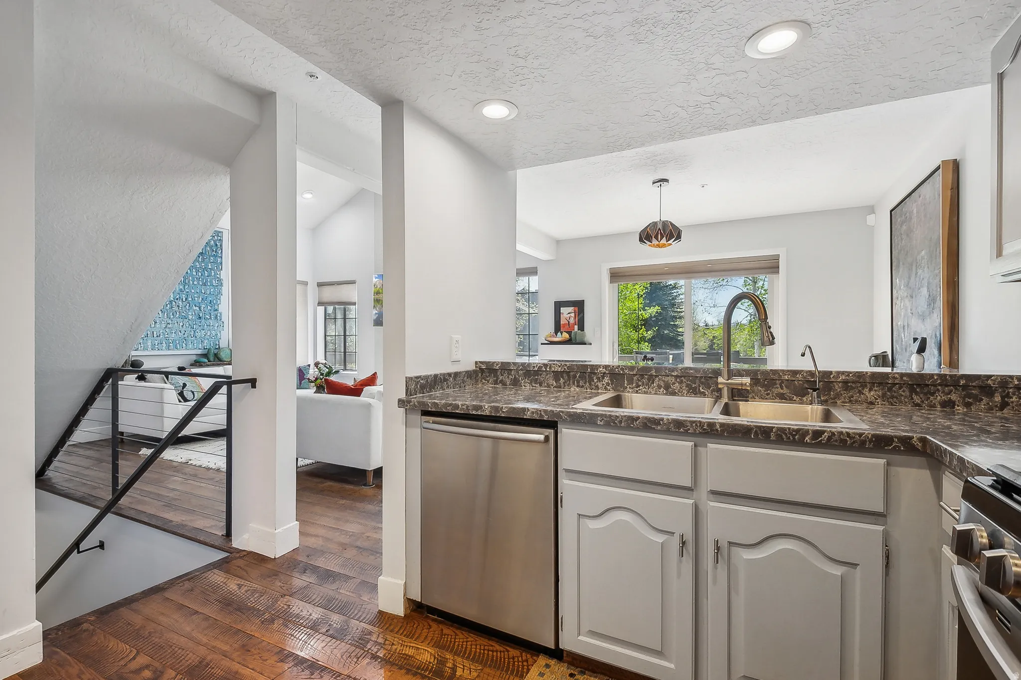 Kitchen featuring a double basin sink with a high-arch faucet, stainless steel dishwasher, wood-finish flooring, and recessed lighting