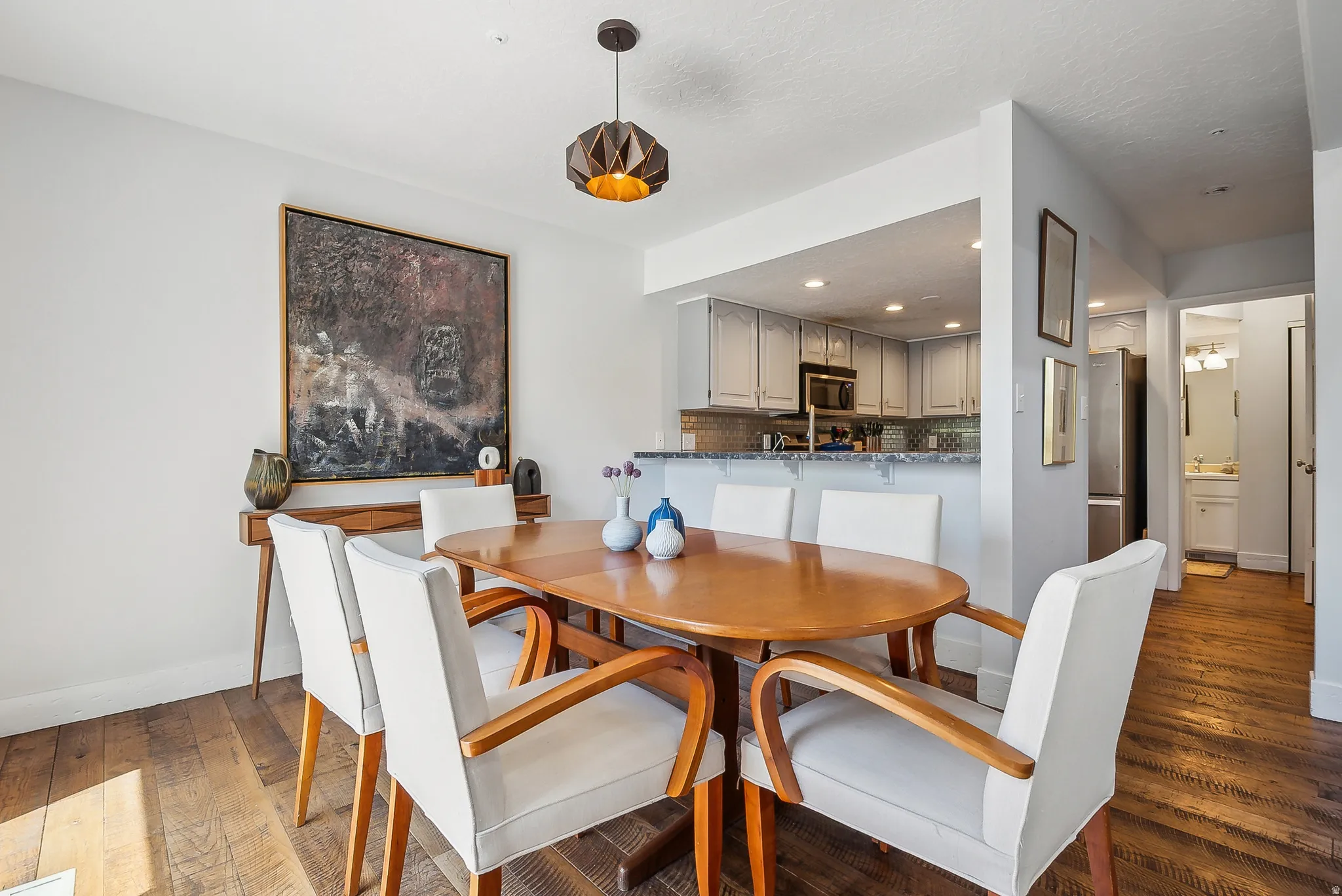 Dining area with wood-finish flooring and a contemporary geometric pendant light fixture