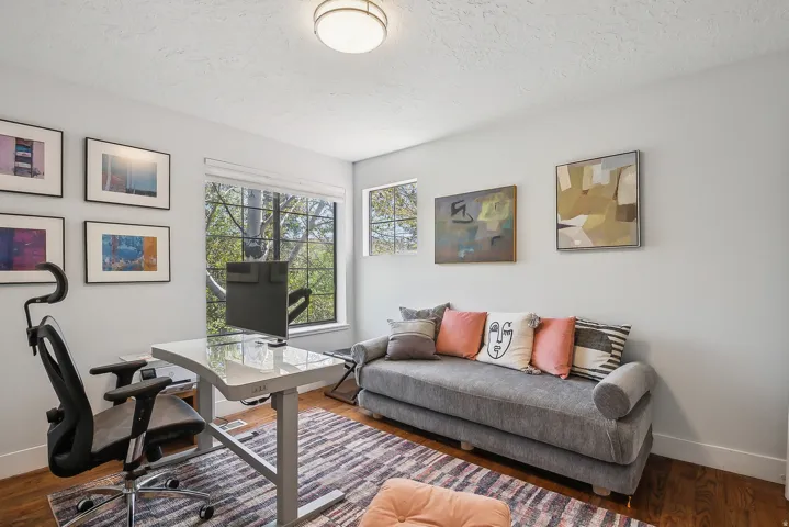 Versatile room featuring hardwood flooring, multiple windows providing natural light, recessed ceiling light fixture, and a neutral wall color