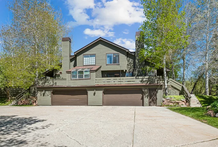 Multi-level exterior with horizontal siding, two integrated garage doors, and multiple balconies