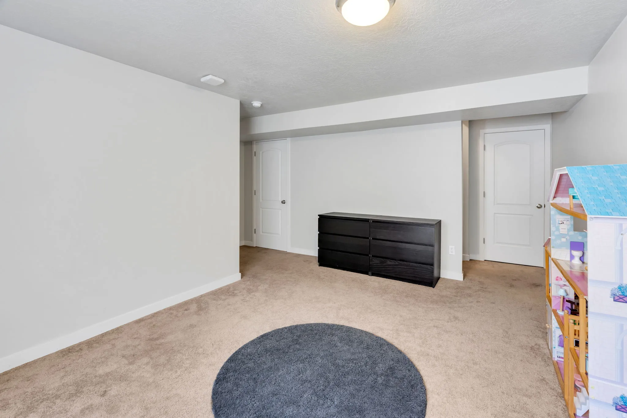 Carpeted interior space featuring light-toned walls, white trim, and a flush-mount ceiling light fixture