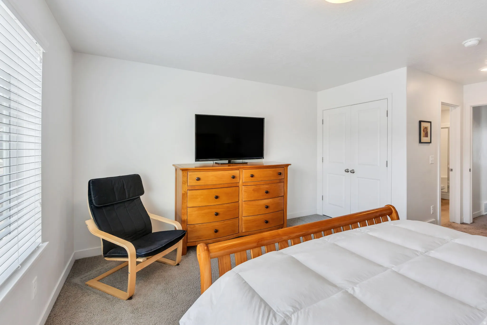 Primary bedroom featuring light gray carpet flooring, white walls, and a window with horizontal blinds